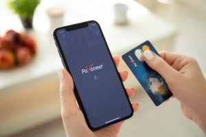 payoneer card in right hand and mobile app in left hand