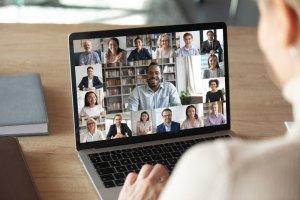 a woman is looking at a laptop screen with a group of people on it and a book on the desk