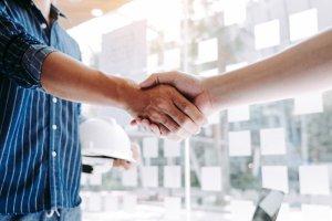 a man and a woman shaking hands in front of a hard hat and hard hat on a hard hat rack